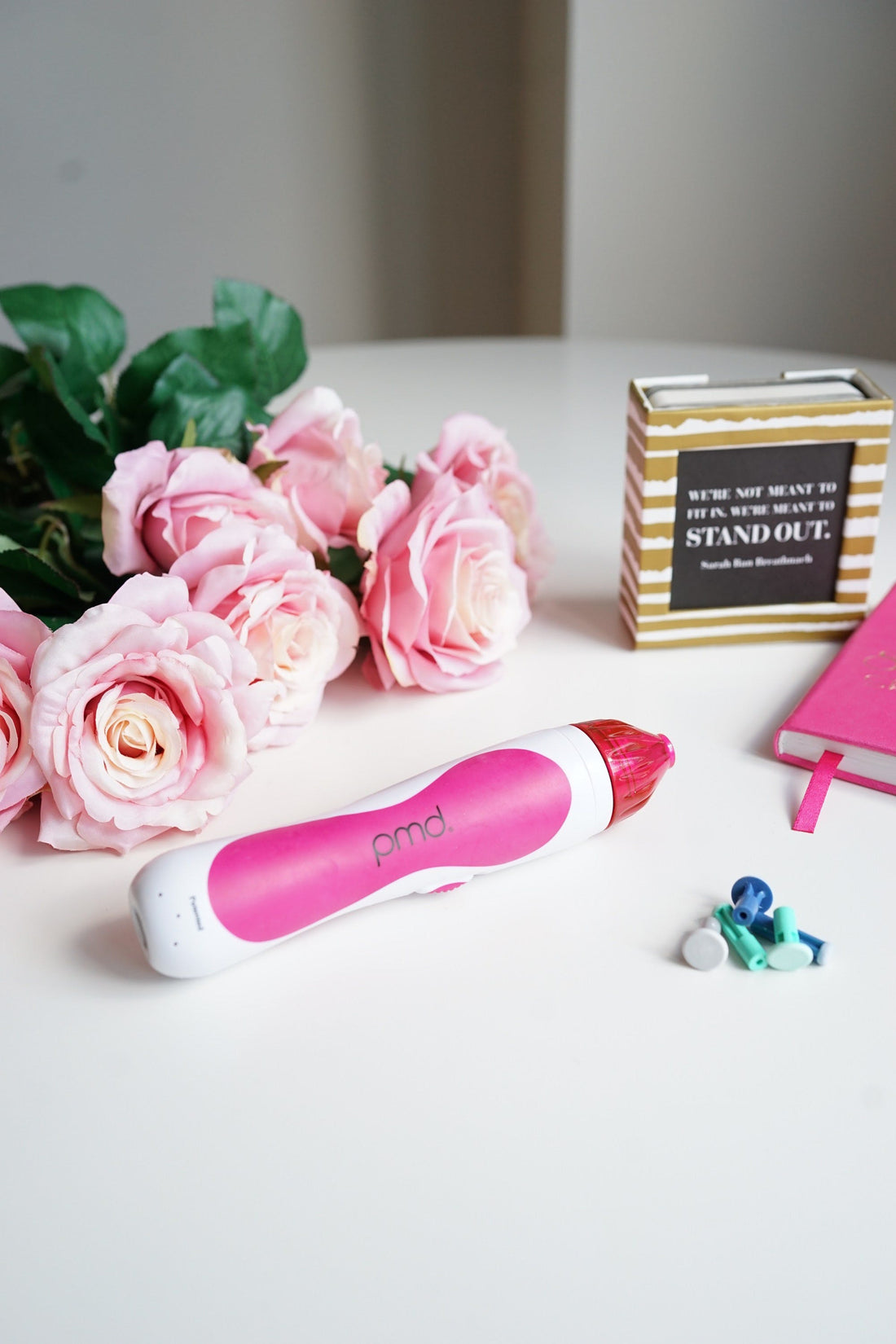 PMD Personal Microderm Classic in pink on counter top with flowers and discs