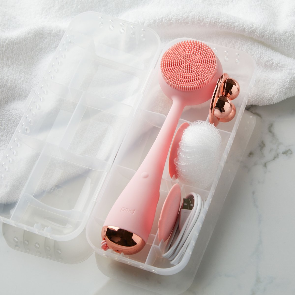 4003-Case?PMD Clean Body Case next to towel with blush PMD Clean Body and accessories inside
