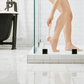 hover-image?woman using blush PMD Clean Body exfoliator attachment to scrub heels in shower